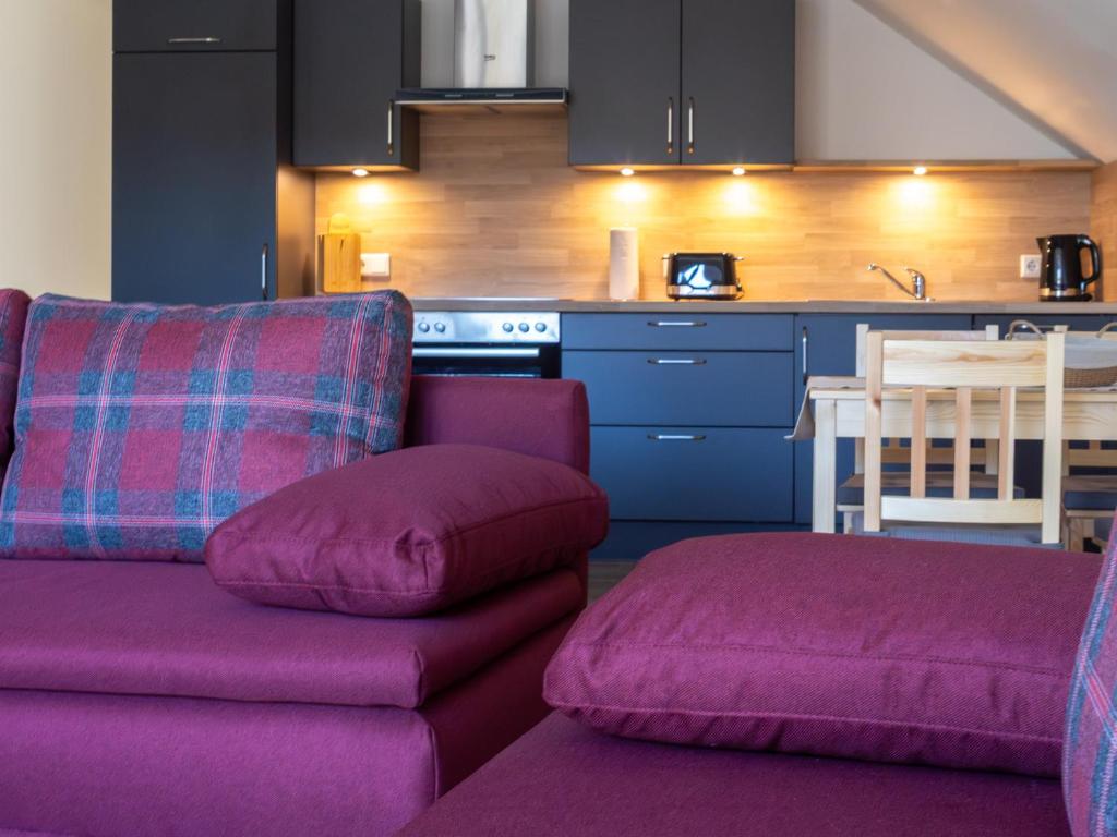 a living room with a purple couch and a kitchen at Kraatzer Ferienwohnungen in Gransee