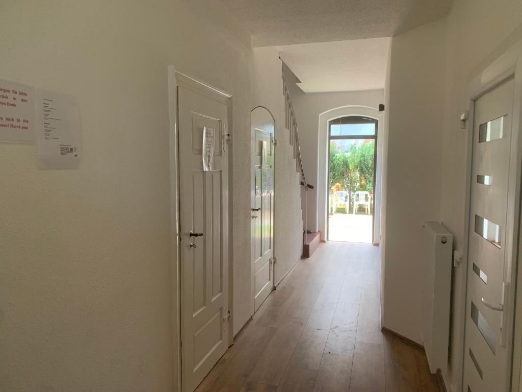 a hallway with white walls and wooden floors and a door at Arnold Apartments 2 in Glauchau