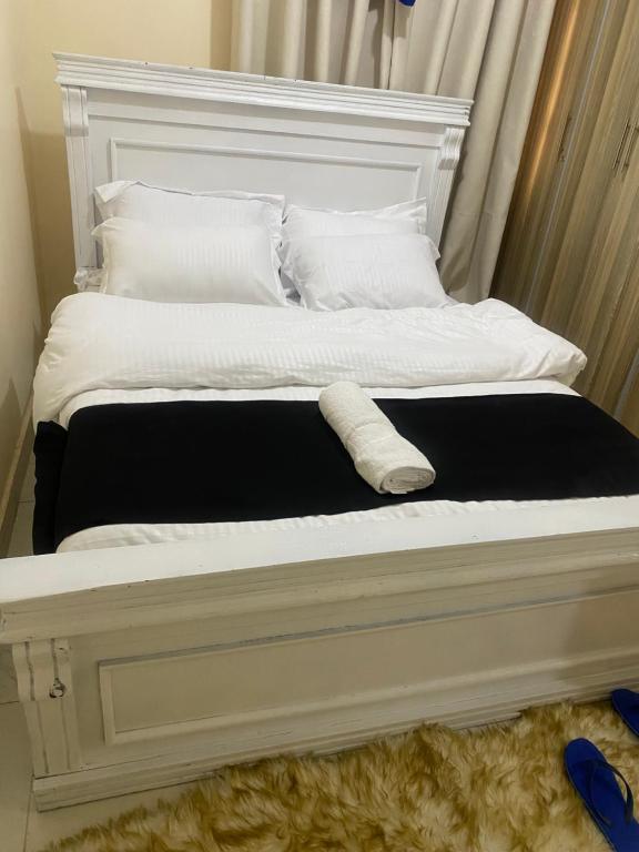a bed with a white headboard with a towel on it at Banas Homes Kakamega in Kakamega