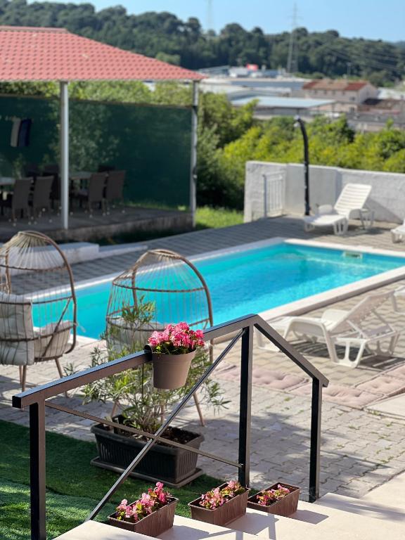 a swimming pool with two chairs and a table with flowers at Vila Neyra in Pula