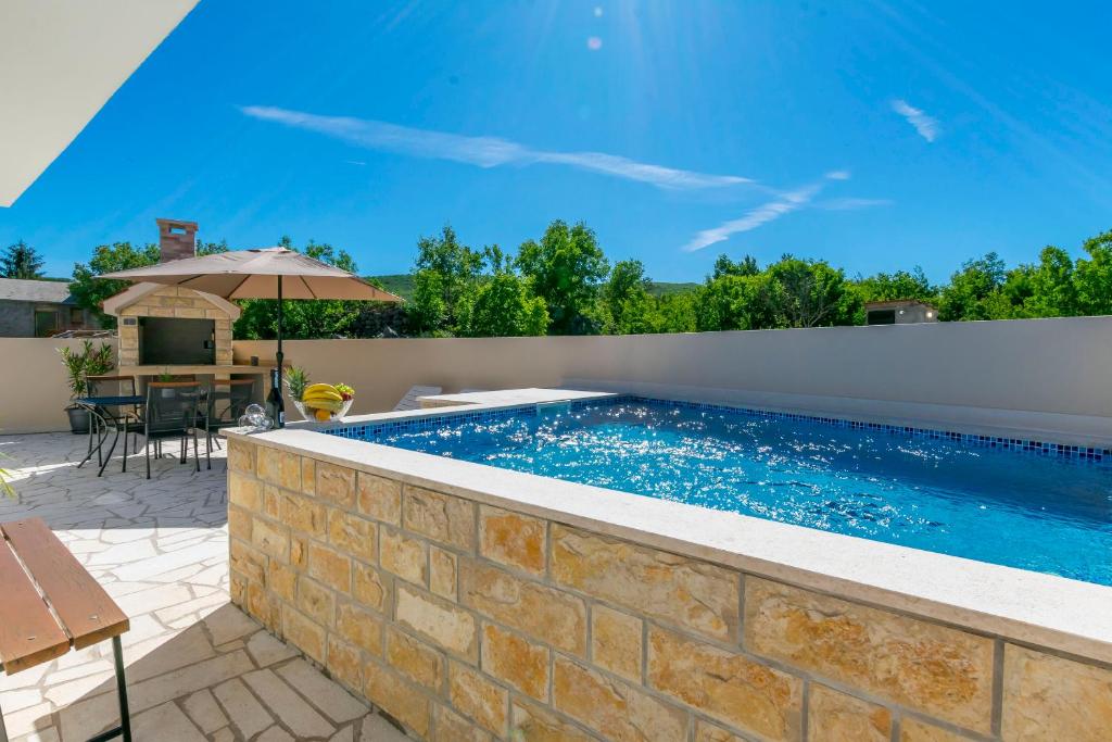 a swimming pool in a backyard with a brick wall at House Romance for two in Zagvozd