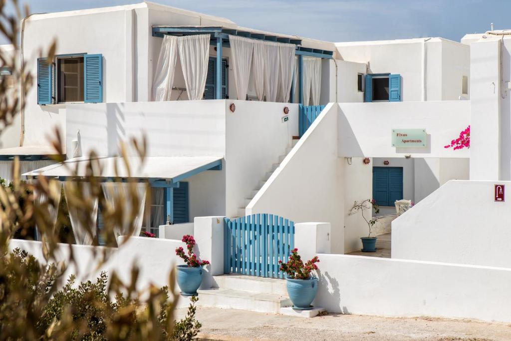 a view of white buildings with blue doors and flowers at Fivos Apartments in Aliki