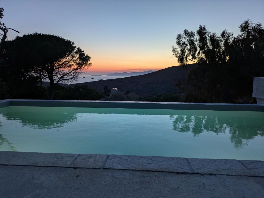 a swimming pool with a sunset in the background at The Priest House in Makrotándalon