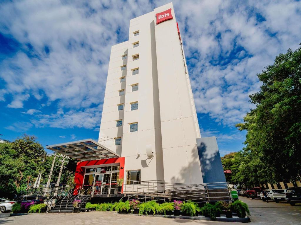 a tall white building with a sign on it at ibis Asuncion in Asunción