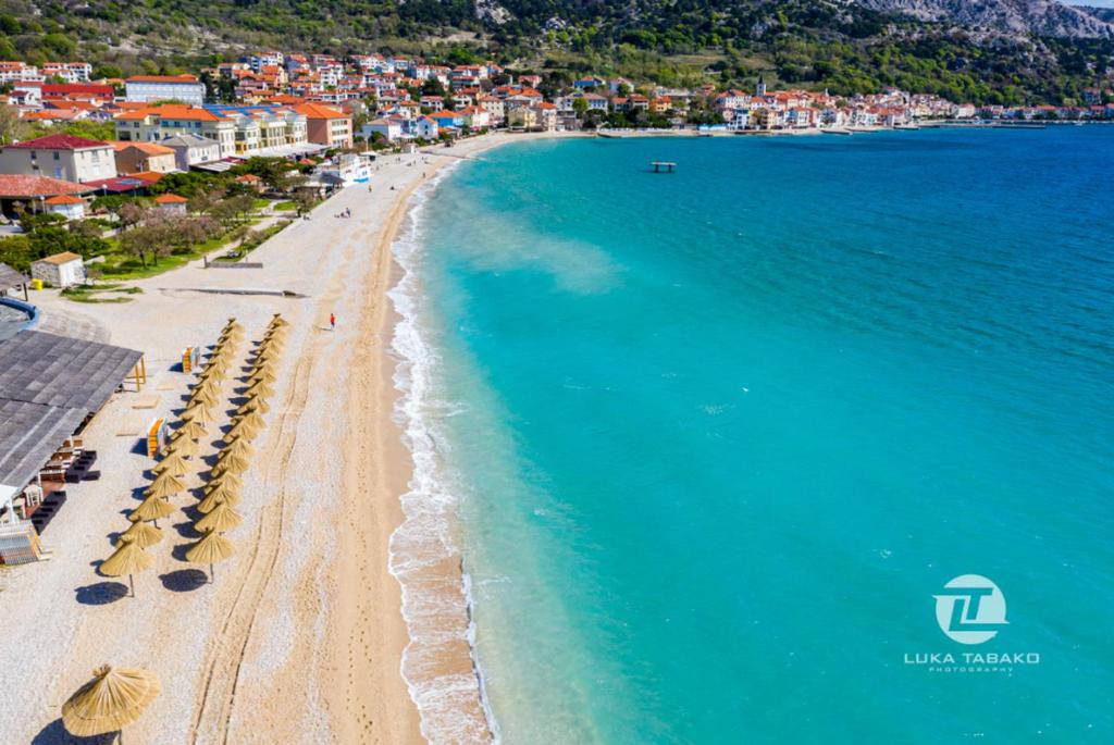 an aerial view of a beach with umbrellas and the ocean at Mandy Apartman in Baška