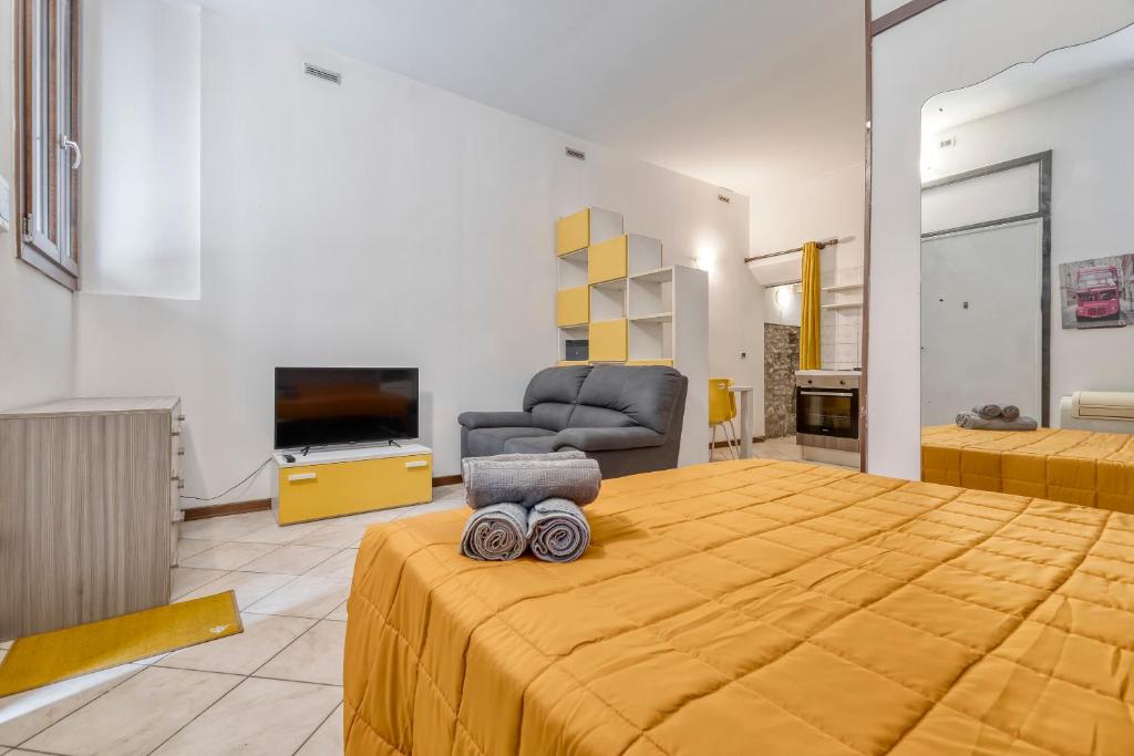 a bedroom with a bed and a chair and a television at Alessia House in Ferrara