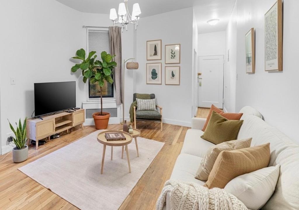 a living room with a white couch and a tv at Charm 2Bd in Upper East Side with Backyard in New York