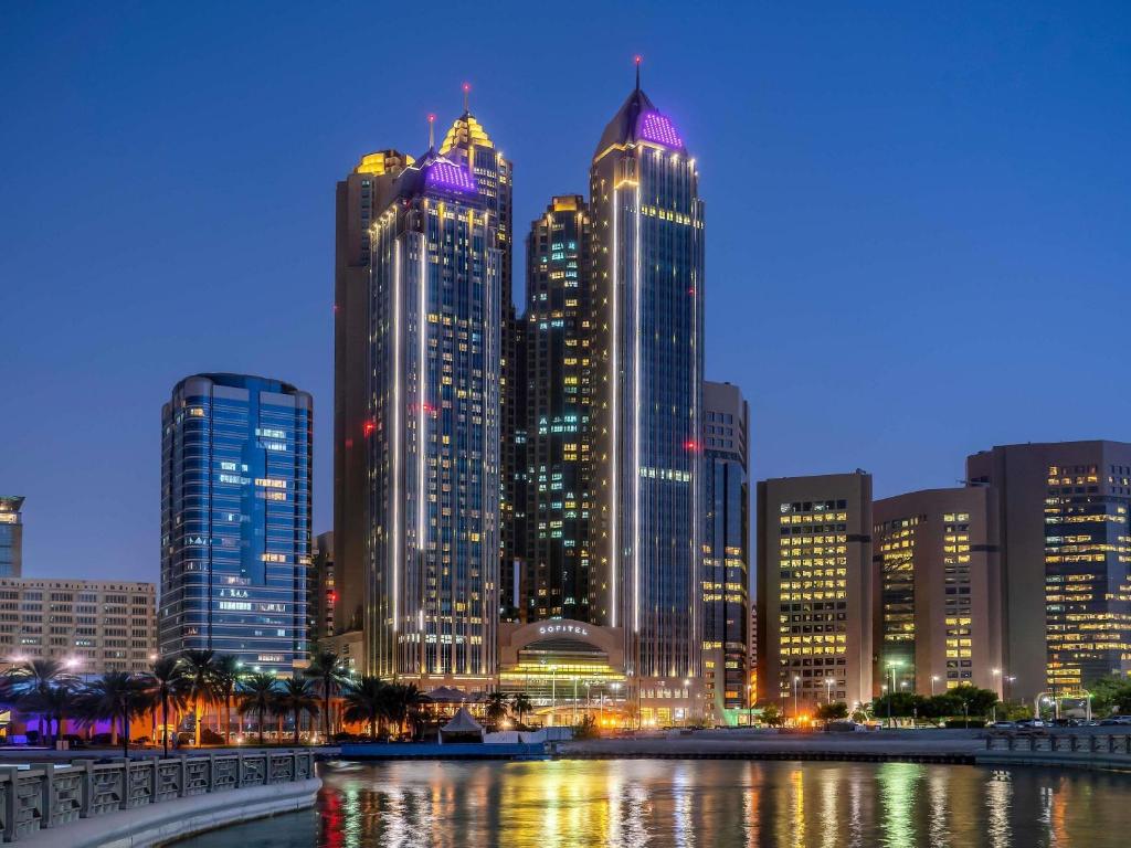a city skyline with tall buildings at night at Sofitel Abu Dhabi Corniche in Abu Dhabi