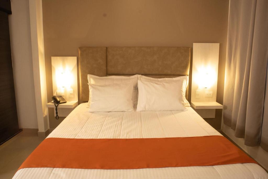 a bedroom with a large bed with two lamps at Los Lirios Hotel Merida in Mérida