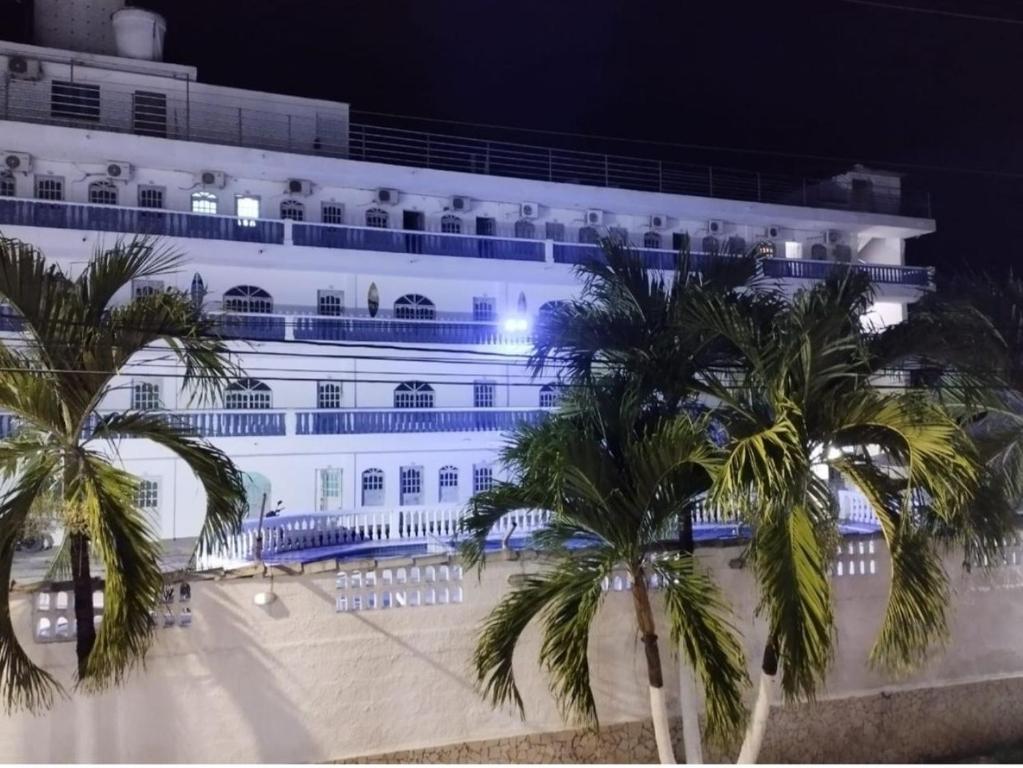 a large white building with palm trees in front of it at Kevin's in Tolú