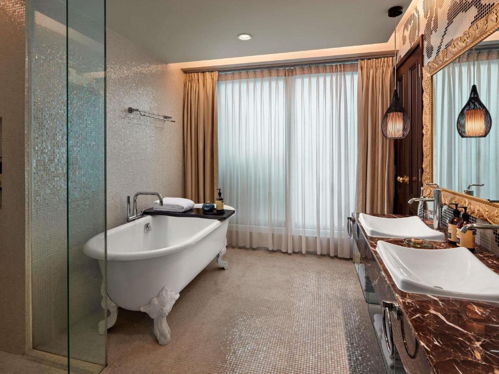 a bathroom with two sinks and a bath tub at Hotel de l’Opera Hanoi - MGallery in Hanoi