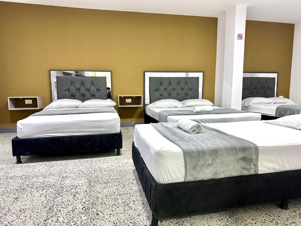 a group of four beds in a room at hotel guayacanes central in Medellín