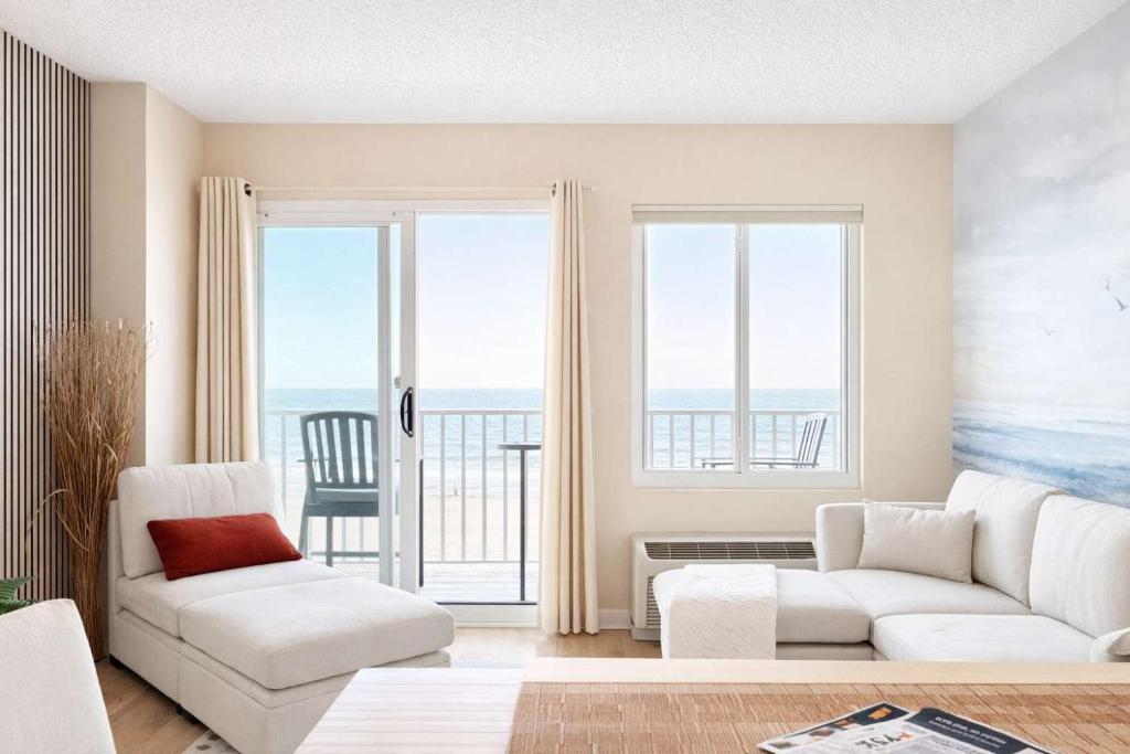 a living room with two white couches and a balcony at Boardwalk Oceanfront Condo with Panoramic Views in Virginia Beach