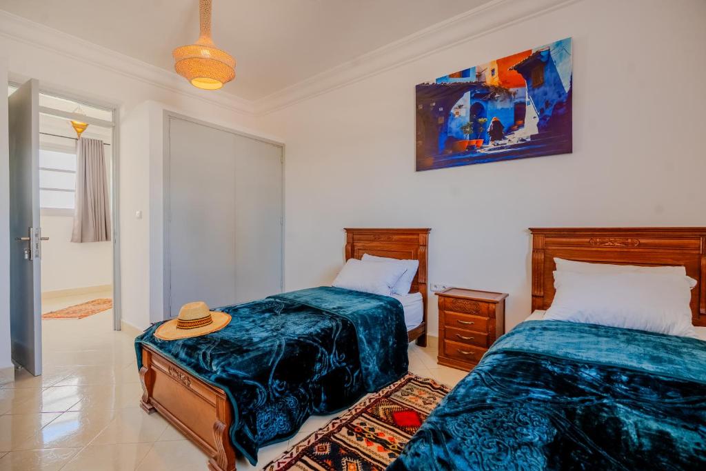 a bedroom with two beds and a hat on a table at Dar Tilila in Essaouira