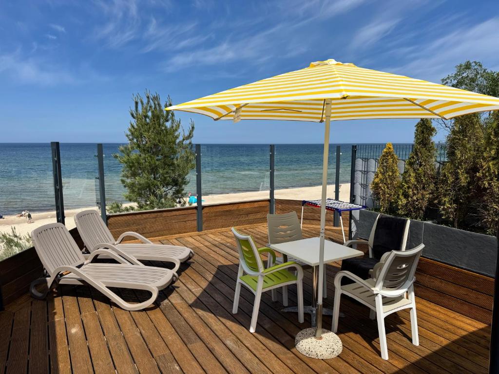 a patio with a table and chairs and an umbrella at WYDMY Apartamenty i Domki Międzywodzie in Międzywodzie
