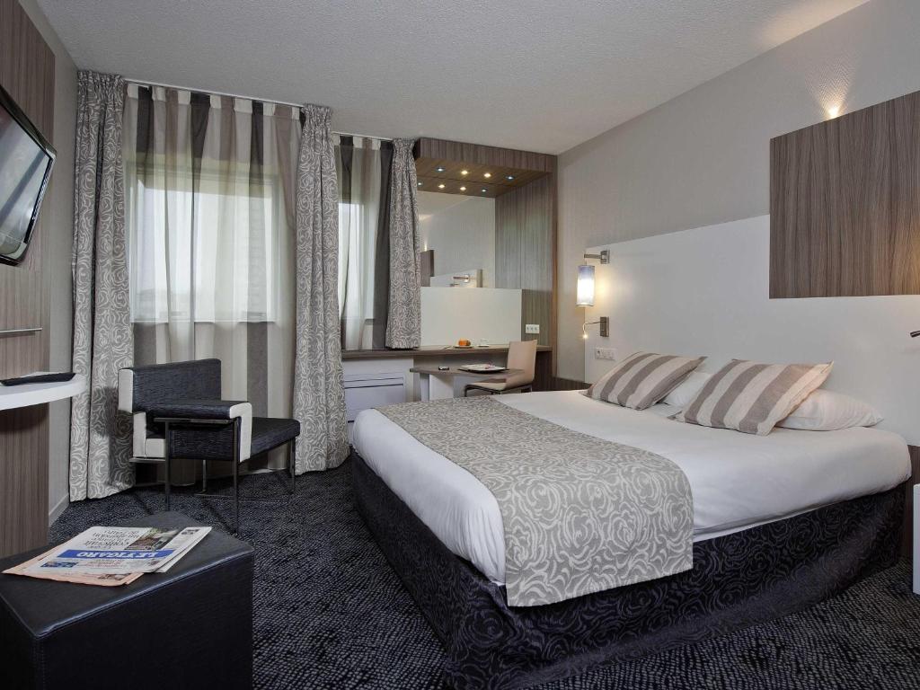 a hotel room with a large bed and a desk at ibis Styles Melun in Rubelles