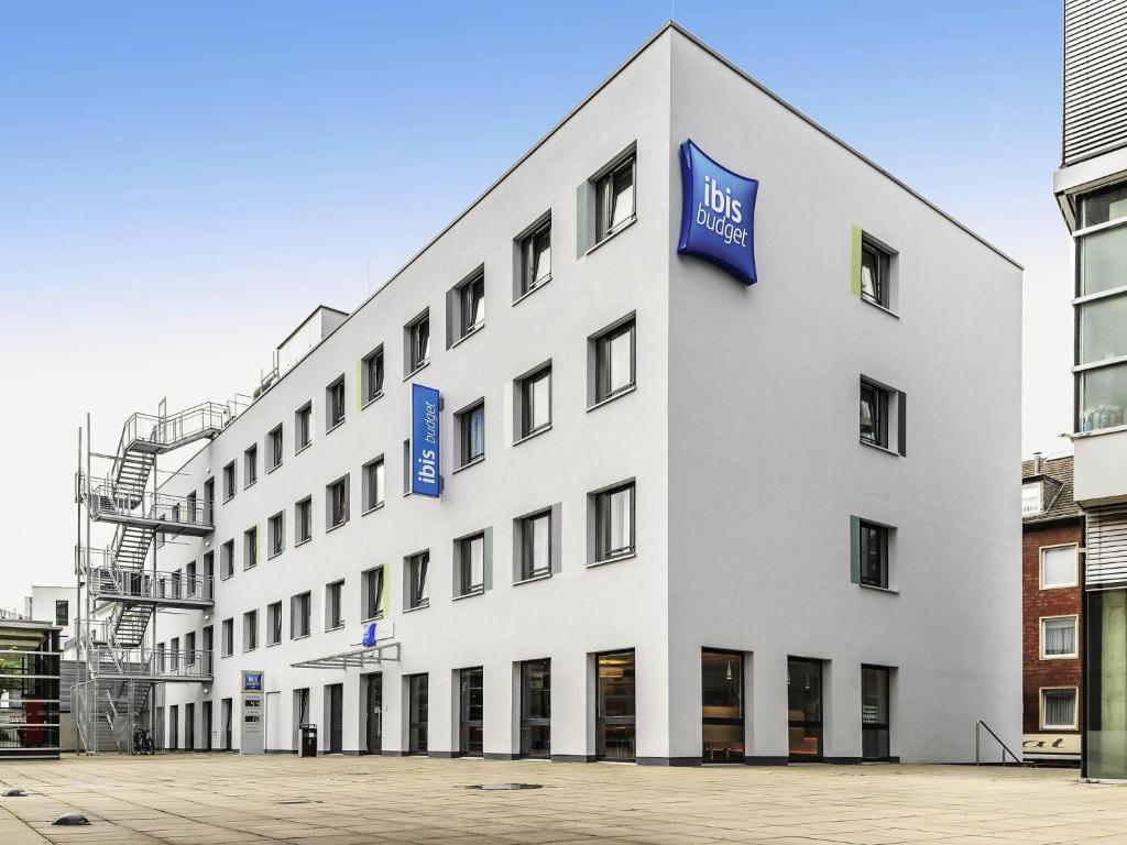 a white building with blue signs on the side of it at ibis budget Aachen City in Aachen