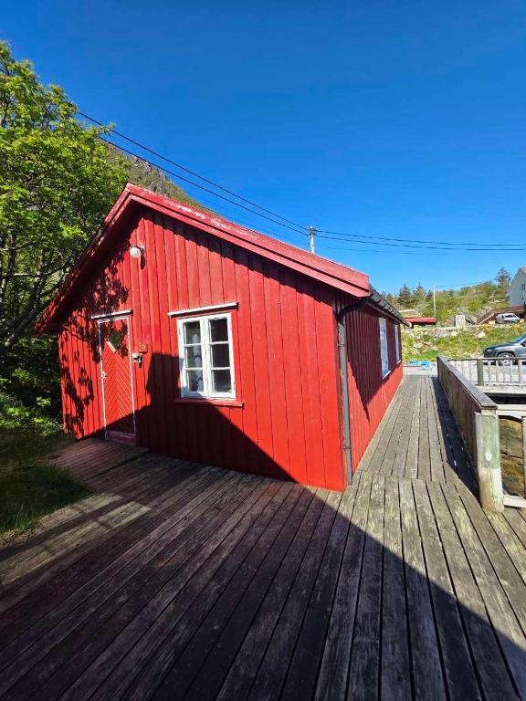 a red building on a wooden deck at Cottage from 1850 in Ballstad in Ballstad