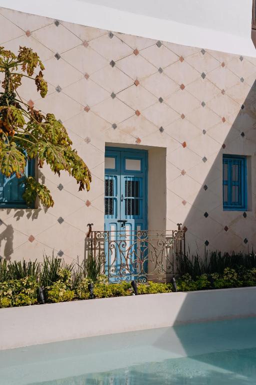 a pink building with a blue door and windows at Villa Mineli in Campeche