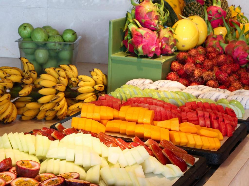 A colorful buffet display of sliced tropical fruit and whole produce.