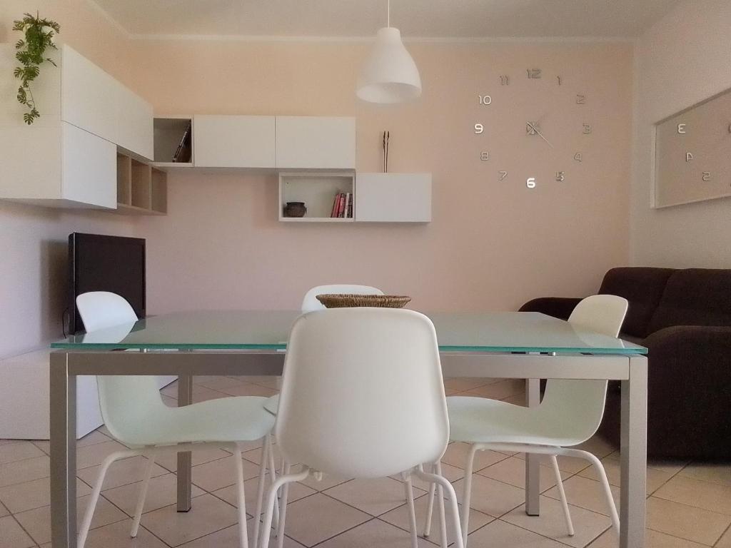 a dining room with a table and white chairs at Casa al parco in Romano D'Ezzelino