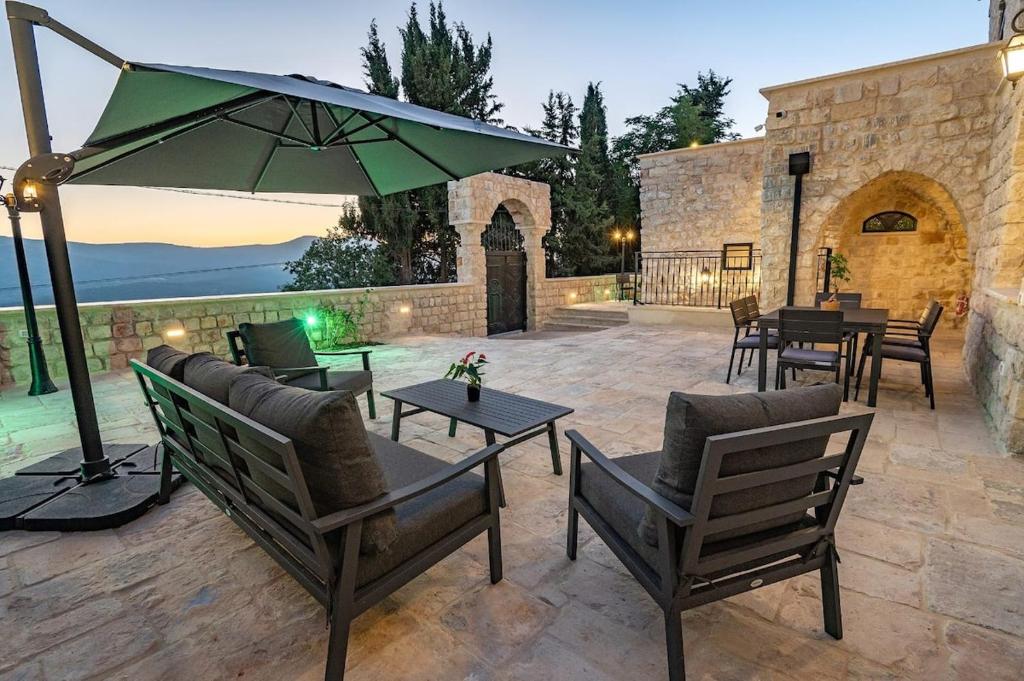 a patio with tables and chairs and an umbrella at Tirat Ronit - טירת רונית in Safed