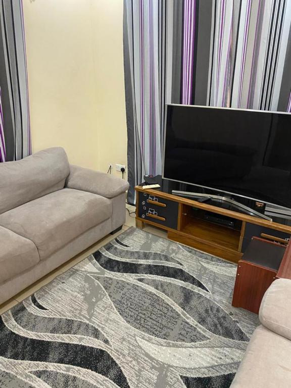 a living room with a couch and a flat screen tv at The Senegambia Hideaway in Amdalai