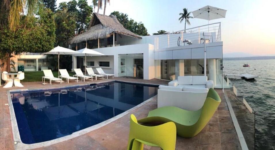 a large house with a swimming pool and chairs at Luxury Villa by the Lake in Tequesquitengo