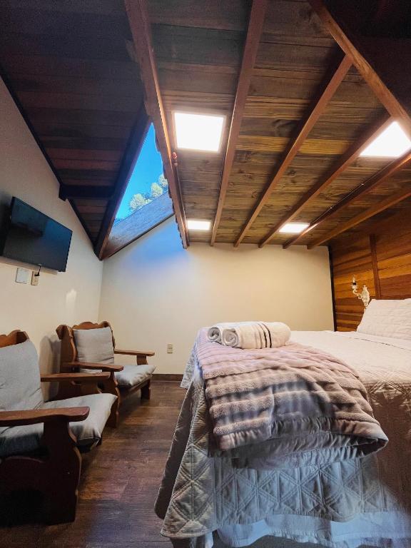 a bedroom with a large bed and a window at Chalé Coração de Monte Verde in Monte Verde