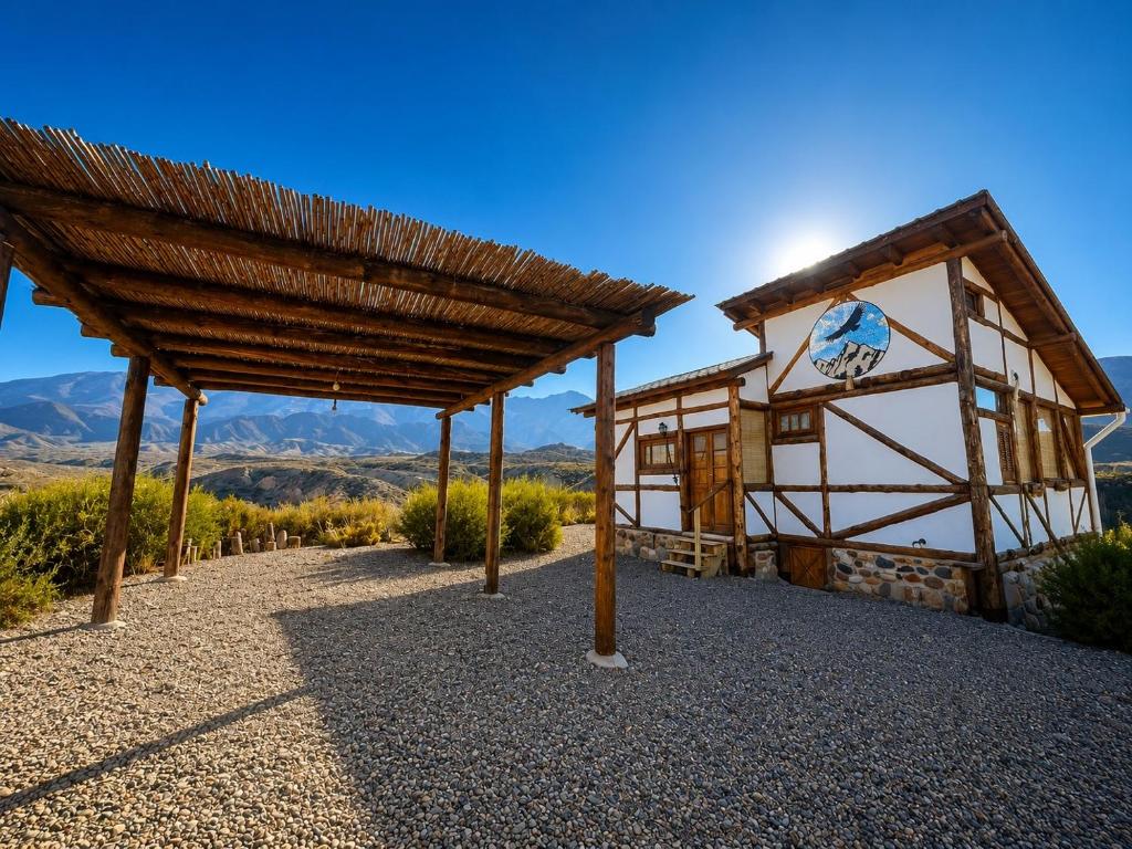 a building with a roof with mountains in the background at Cabaña El Cóndor in Potrerillos