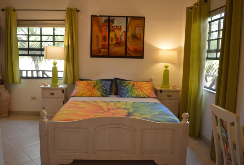 a bedroom with a bed and two windows at Yellow Bird Apartment in Christ Church