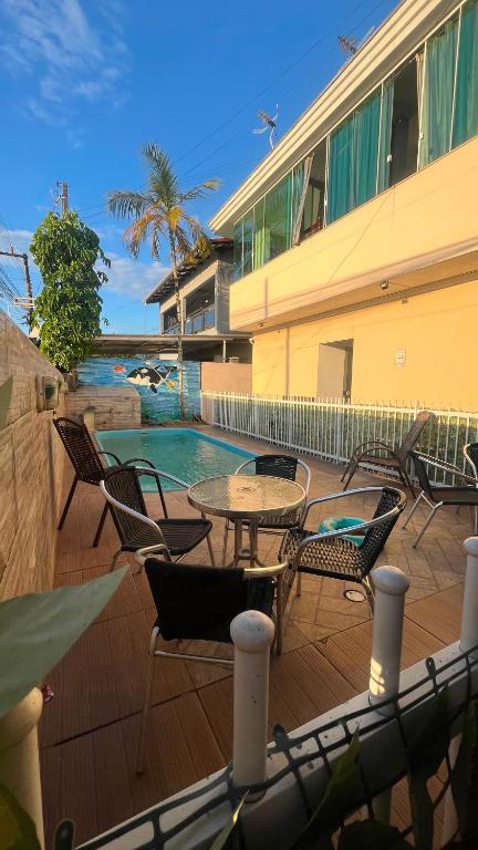 a patio with chairs and a table and a pool at Pousada Ilha do Itacolomi in Penha