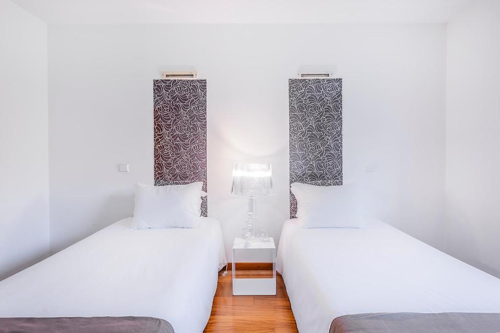 two twin beds in a room with white walls at HI Alvados - Pousada de Juventude in Alvados