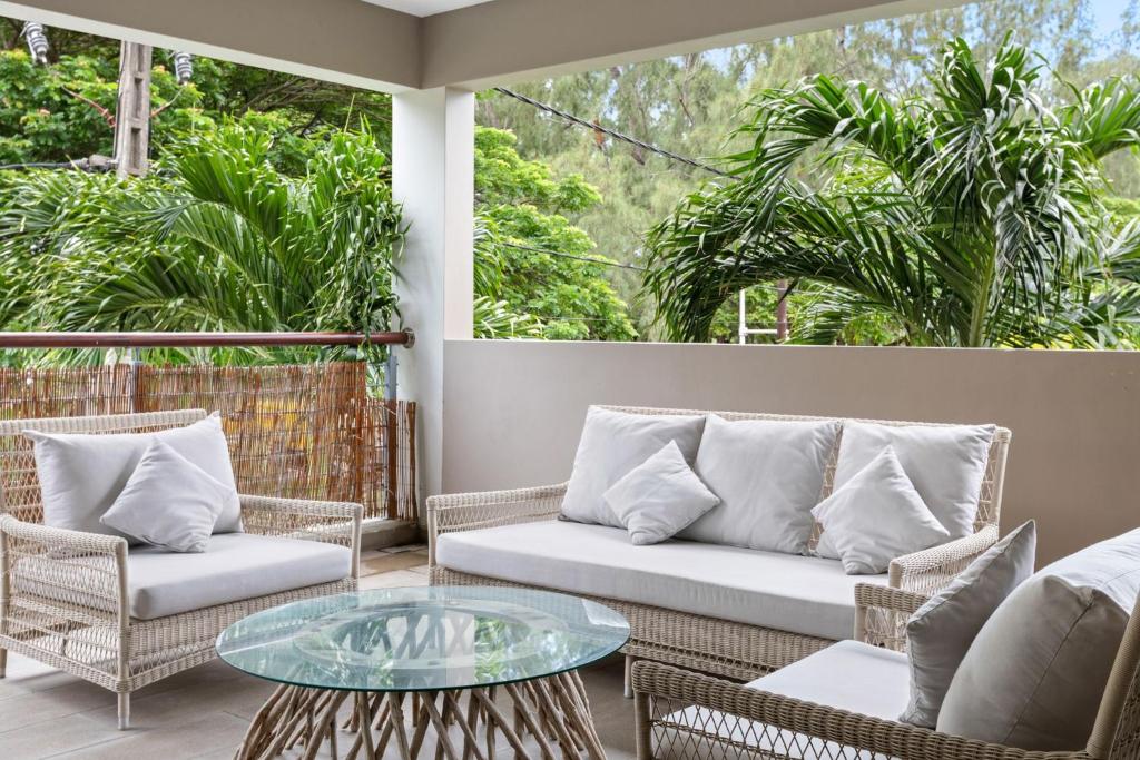 a patio with wicker chairs and a glass table at Element Bay 5 in Cap Malheureux