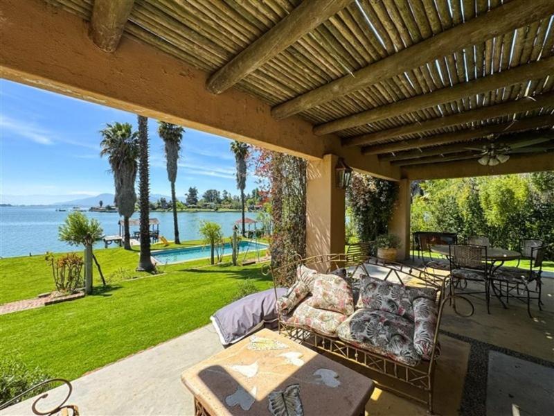 a couch on a patio with a view of the water at El Estero Lago Rapel in El Estero