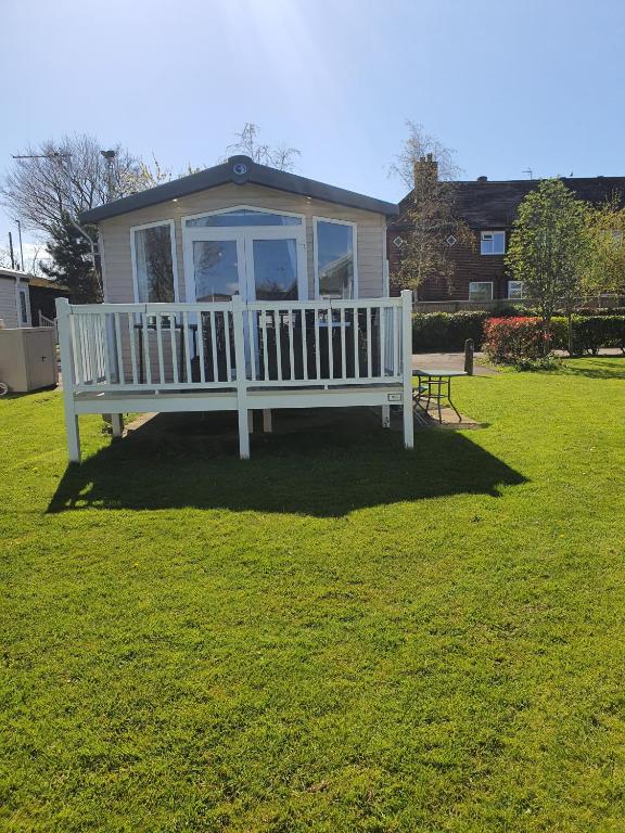 a house with a white bench in a yard at 3-Bed Caravan Sleeps 8 with Enclosed Decking in Fleetwood