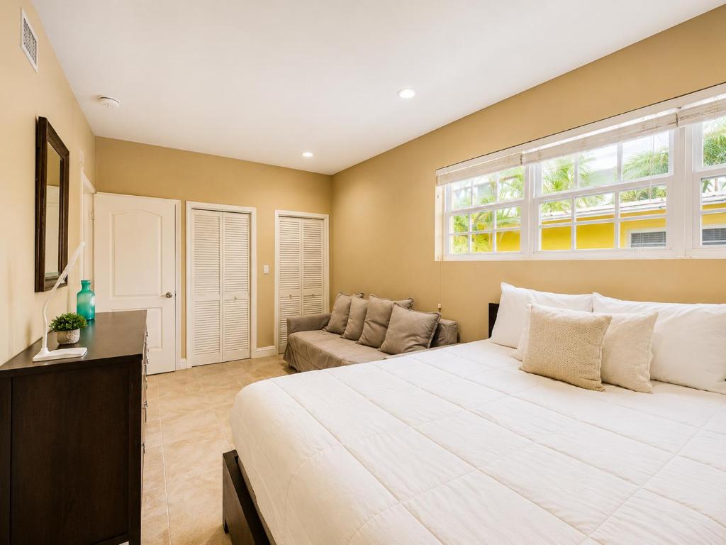 a bedroom with a large white bed and a couch at 2BR with patio, grill, central AC, enclosed yard in Hollywood