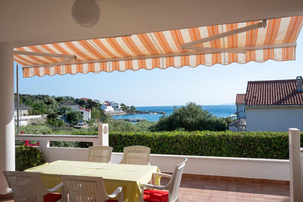 a table and chairs on a balcony with a view of the ocean at Apartments and rooms by the sea Jakisnica, Pag - 4160 in Lun