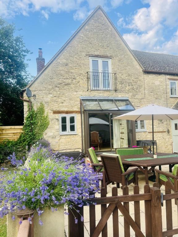 a house with a patio with a table and chairs at The Old Coach house- a delightful home from home in Witney