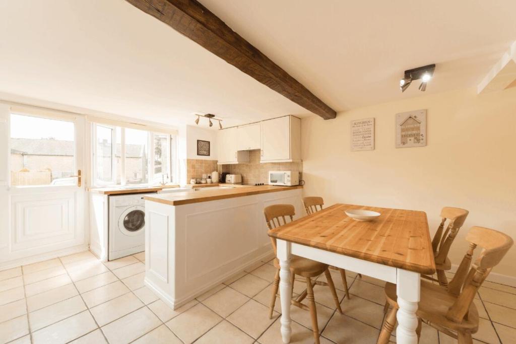 a kitchen with a wooden table and a table and chairs at Mill View-an idyllic base to explore The Cotswolds in Northleach