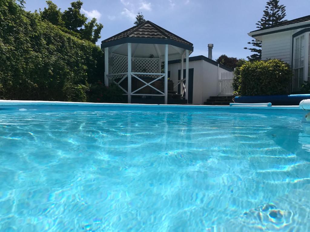 einen Pool mit Pavillon vor einem Haus in der Unterkunft Te Moana Bed & Breakfast in Waikanae