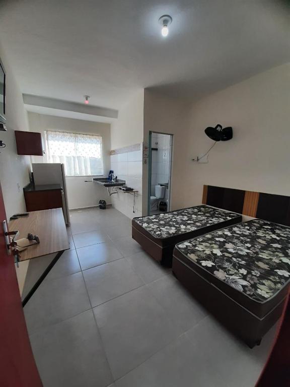 a bedroom with two beds and a kitchen with a sink at Flat em Varginha, Minas Gerais com Lazer Total e Estacionamento Gratuito in Varginha