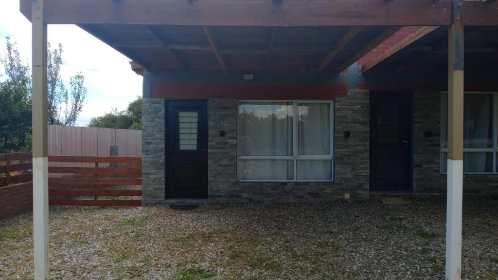 a brick house with a black door and a fence at Departamento Fede 1 in Carpintería