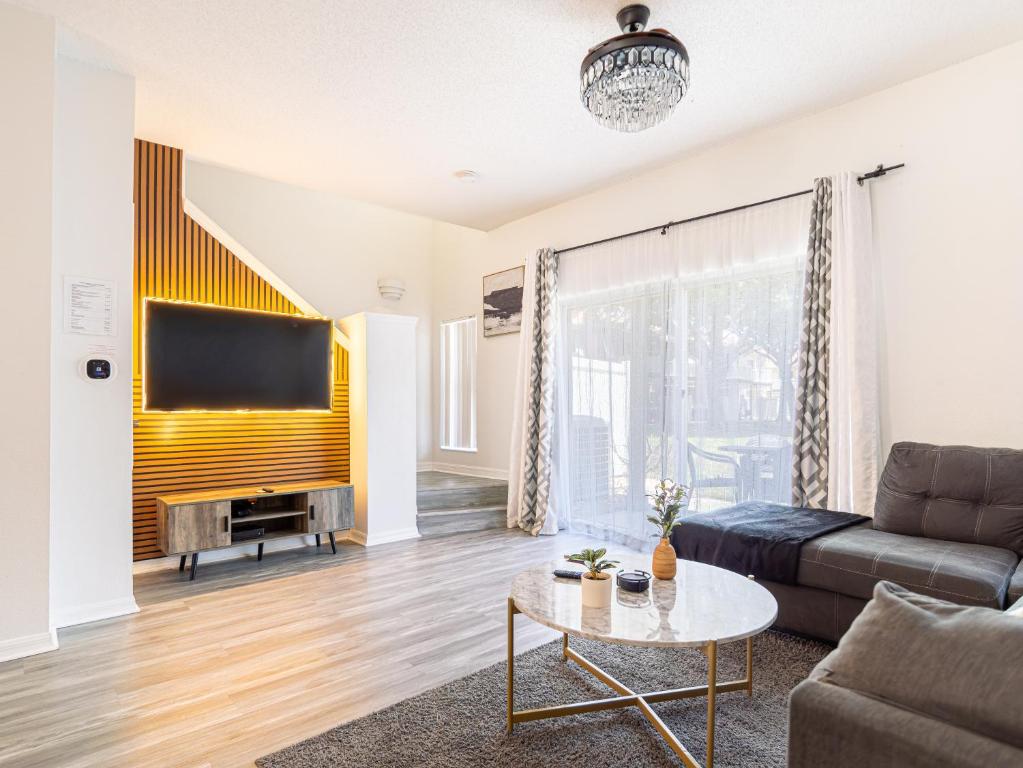 a living room with a couch and a tv at The Enchanted luxe Townhome in Kissimmee