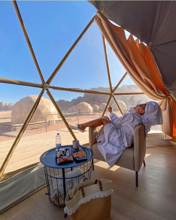 a person laying in a tent with a table at Ain Rum Luxury Camp in Wadi Rum