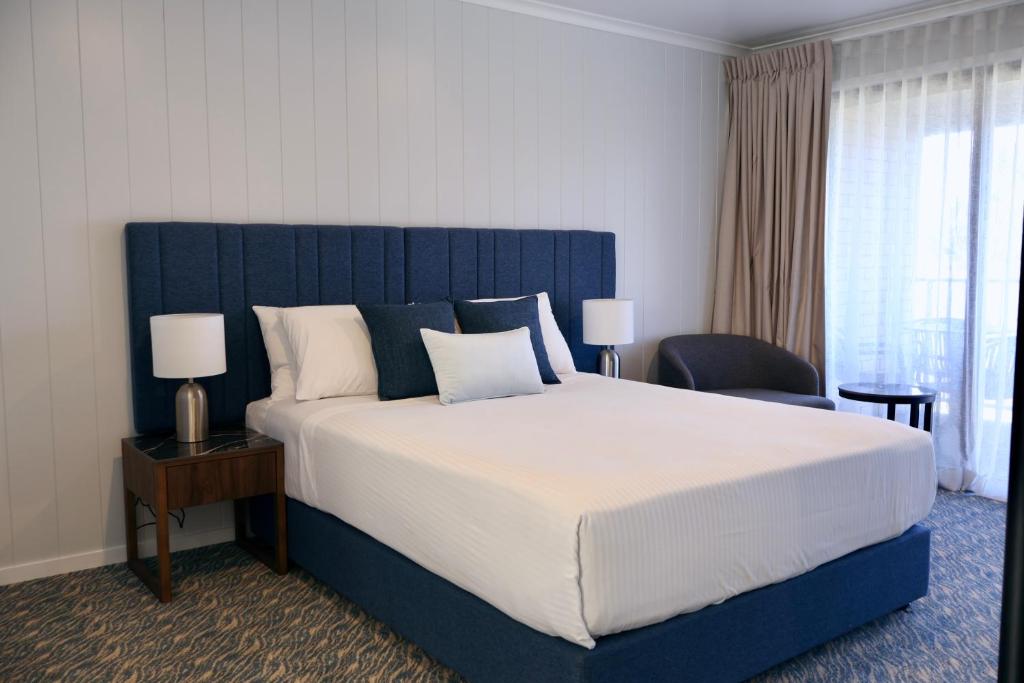 a bedroom with a large bed with a blue headboard at Victory Hotel Motel Gympie in Gympie
