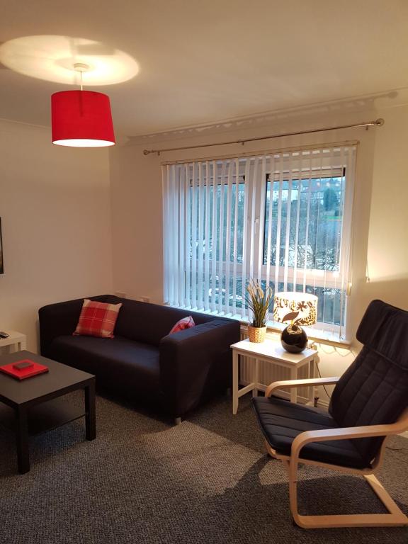a living room with a black couch and a window at Bathgate Contractor and Business Apartment in Bathgate