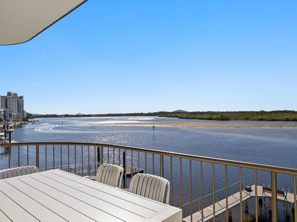 a table and chairs on a balcony with a view of the water at Wharf Lodge River View Apartment in Maroochydore