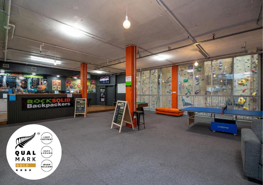 a room with a rock wall and a pool table at Rock Solid Backpackers Rotorua in Rotorua