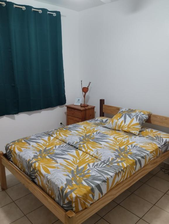 a bedroom with a bed with a yellow and black comforter at Le Courbaril in Le Gosier